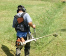 photo d'un homme entrein de passer le debroussaileur dans une fosse